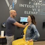 Fishers, IN chiropractor performing a posture and shoulder-height assessment for scoliosis screening in a modern clinic room